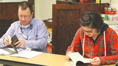 Advanced Senior Social Science teacher Kyle Smith (left) sits beside senior Megan Tunell while skimming through “Nigger: The Strange Career of a Troublesome Word” by Randall Kennedy on Feb. 20 in Room 235. Photo illustration by Creede McClellan
